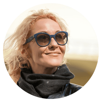 Happy woman in sunglasses enjoying outdoors with a scarf, representing a positive client testimonial experience.