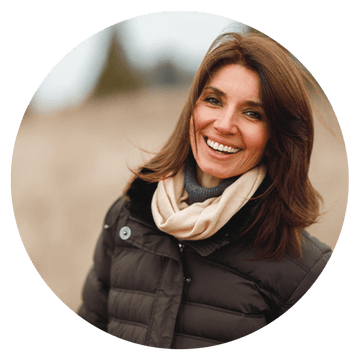 Happy woman in a winter coat smiling outdoors, embodying client testimonial positivity and satisfaction.