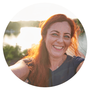 Harmonie Daily client testimonial featuring a smiling woman with red hair by the water during sunset.