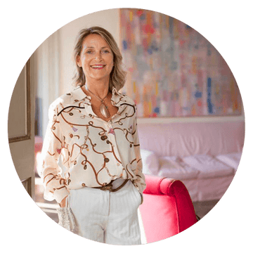 Harmonie Daily client testimonial featuring a smiling woman in a stylish blouse standing in a bright, inviting interior.