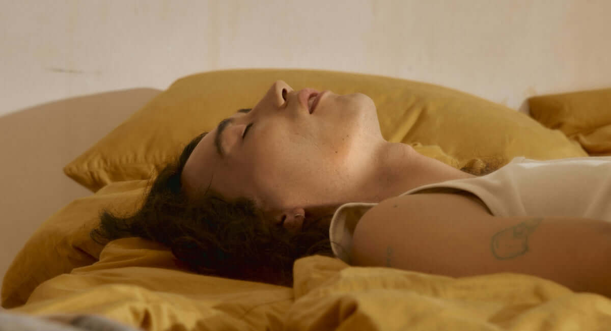 Femme reposant paisiblement dans son lit, symbolisant un sommeil réparateur en ménopause.