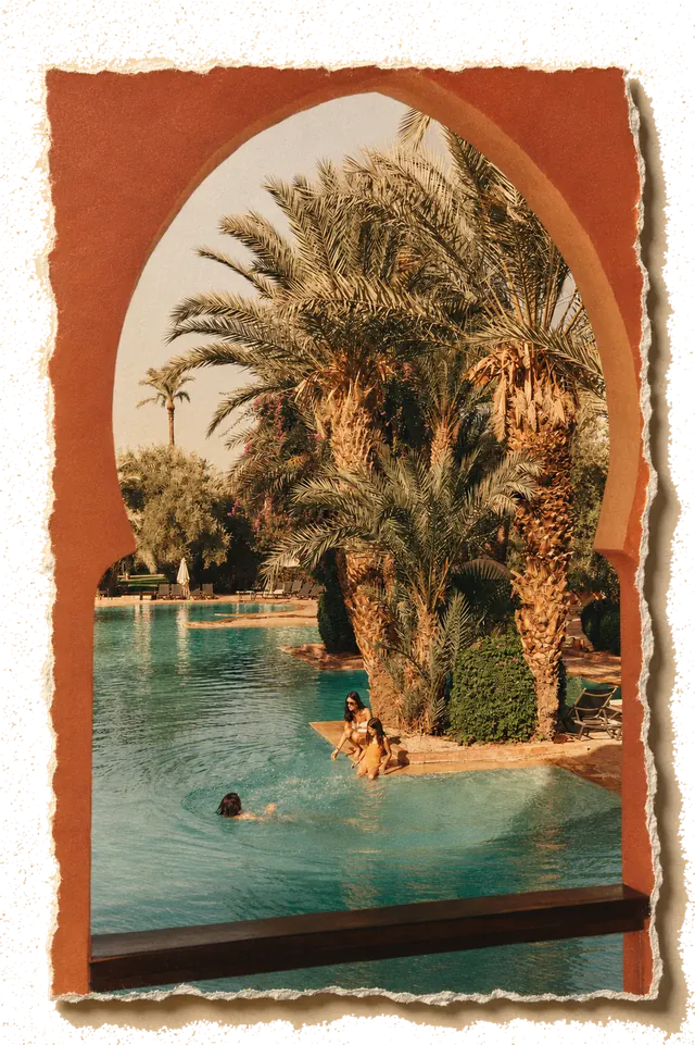 La piscina del resort vista da un arco color terracotta, palmeti